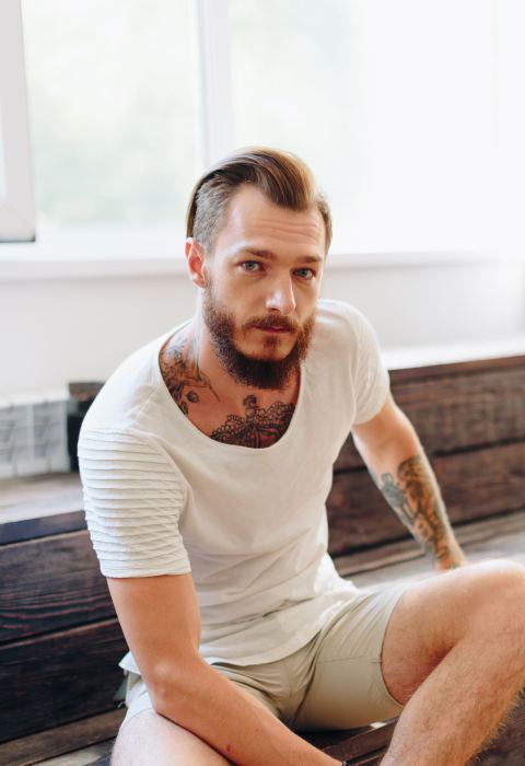 Homme barbu tatoué assis